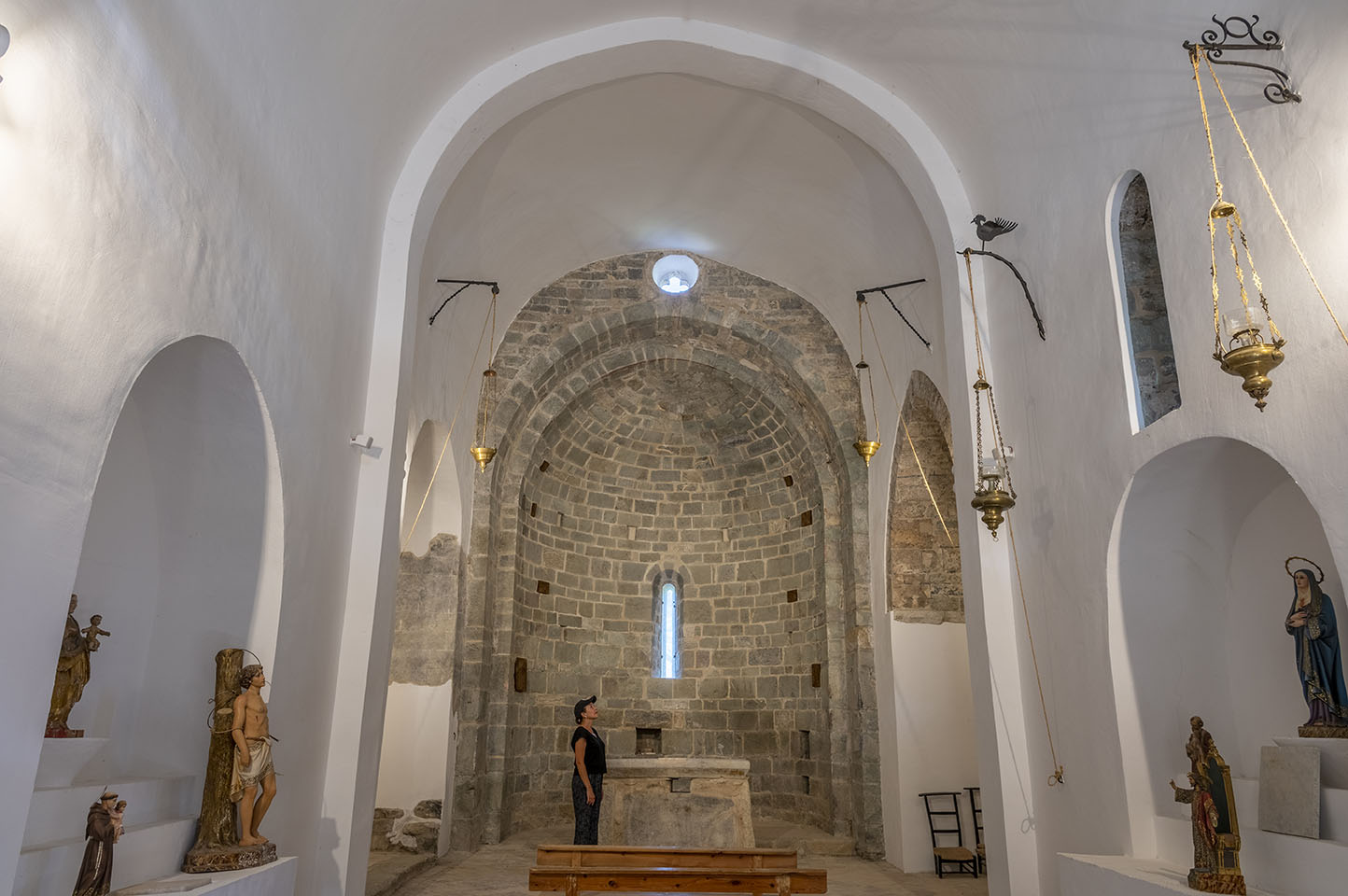 Vista de l’interior de l’església de l’Assumpció de Cóll, amb les parets emblanquinades i l’absis semicircular i l’altar al fons.