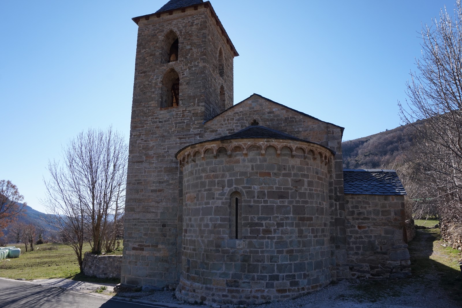 Exterior de l’església de l’Assumpció de Cóll vista des de la part del darrere amb l’absis en primer terme.