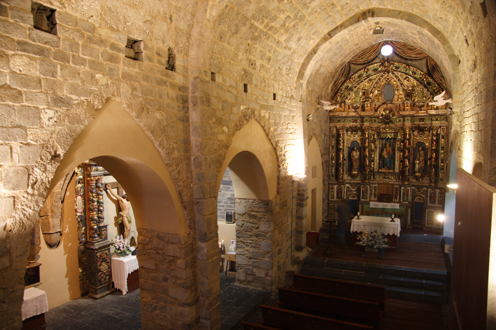 Vista de l’interior de l’església de la Nativitat de Durro amb l’altar i un gran retaule barroc al fons.