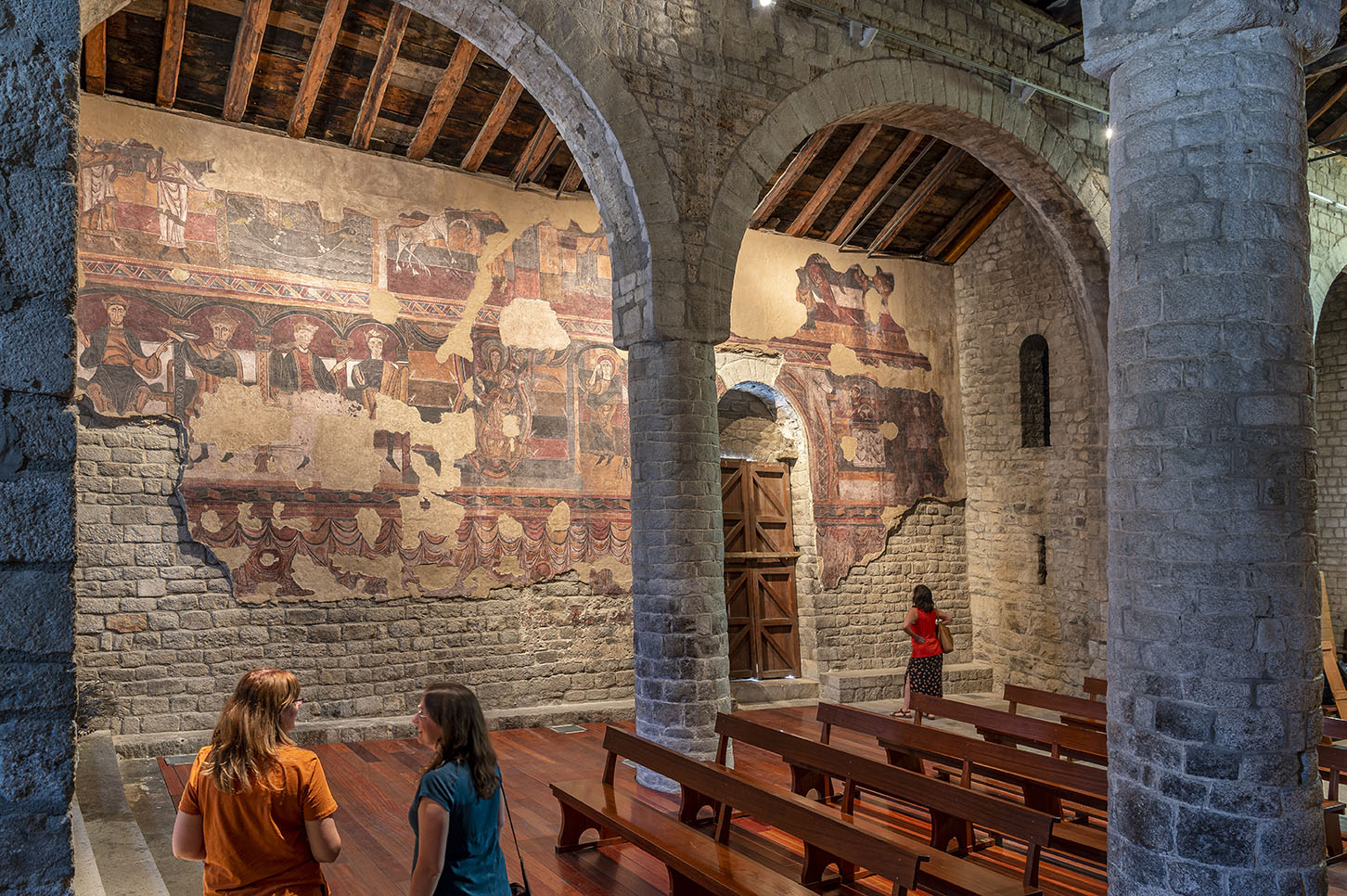 Pintures murals interiors del mur sud de l’església de Santa Maria de Taüll amb el pilar i els arcs en primer terme.
