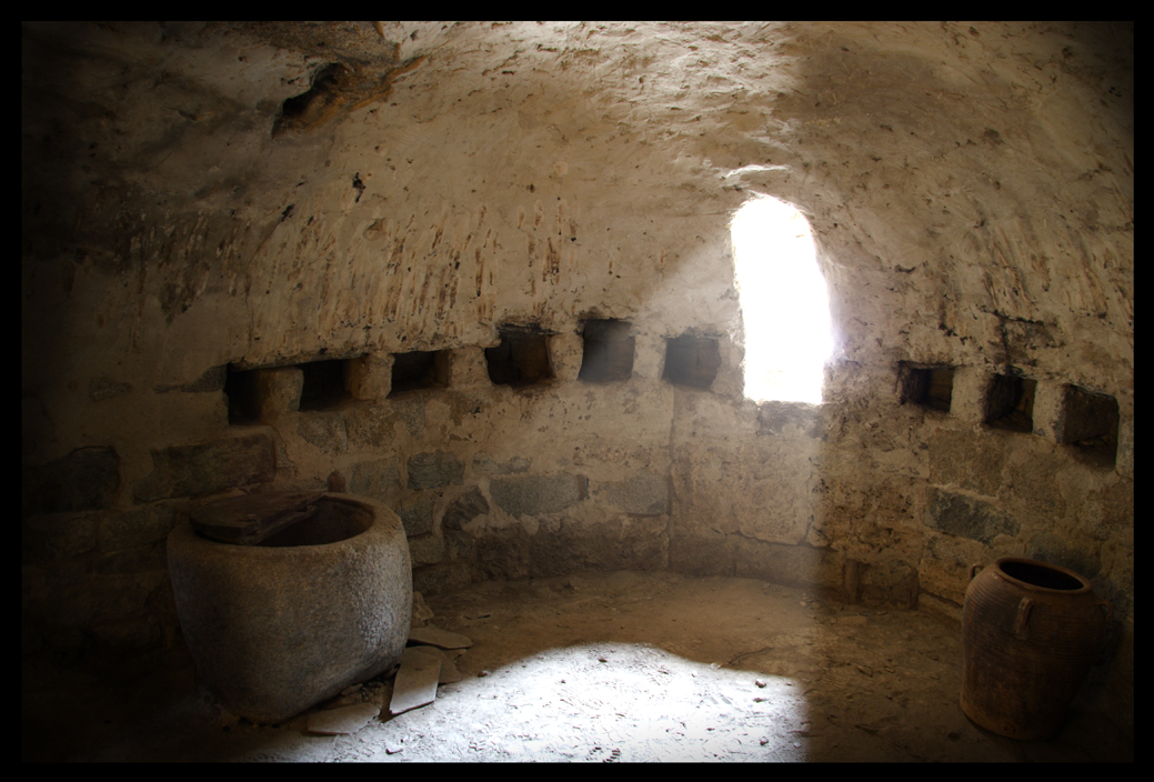 Cripta de l’església de Santa Maria de Cardet amb una pica d’oli romànica i la llum entrant per l’única obertura.
